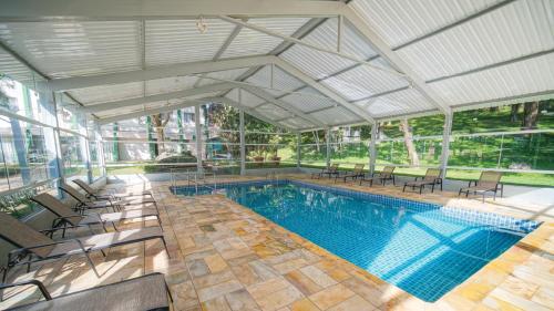 an indoor swimming pool with chairs and a large building at Eldorado Atibaia Eco Resort in Atibaia