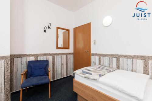 a bedroom with a bed and a blue chair at Töwerland Zimmer 1 in Juist