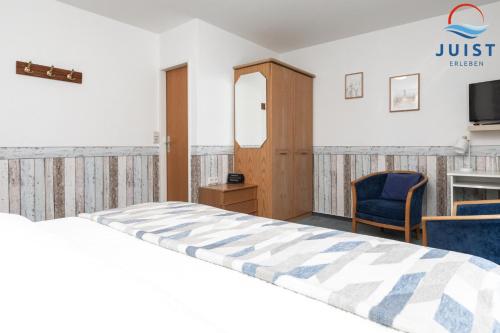 een slaapkamer met een bed, een stoel en een tv bij Töwerland Zimmer 2 in Juist