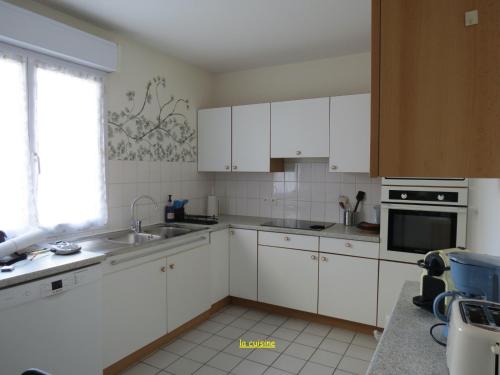a kitchen with white cabinets and a sink and a window at Home SAINT-MAURILLE in Angers