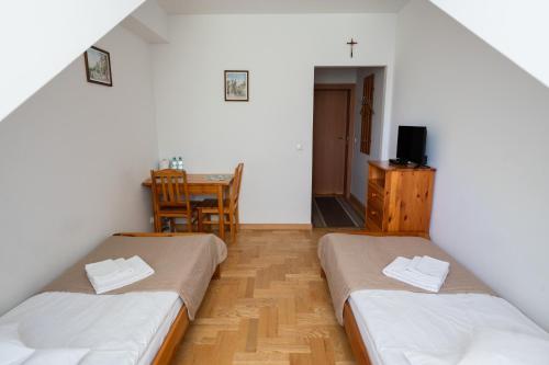 two beds in a room with a table and a chair at Pokoje Gościnne Dom św. Szymona in Kraków