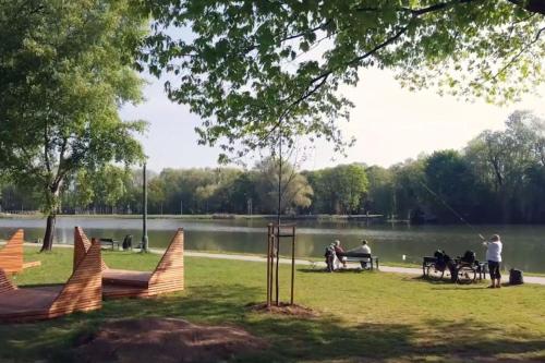 a park with people sitting at tables near a lake at Twoje prywatne SPA - jacuzzi, sauna, tężnia solankowa in Kraków