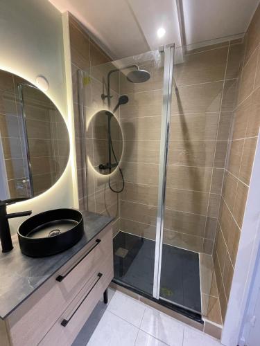 une salle de bain avec une douche avec un lavabo et un miroir dans l'établissement appartement cosy à 100m de la mer !, à Cucq