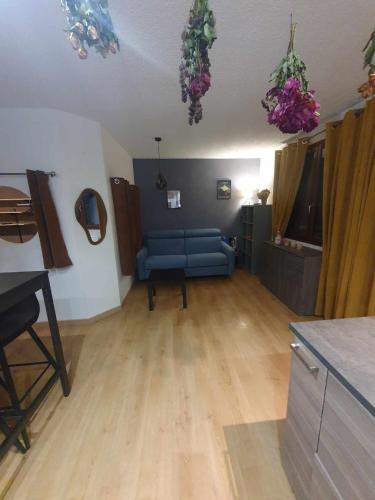 a living room with a blue couch and wooden floors at Appartement VUE SUR LES MONTAGNES in Saint-Pierre-de-Chartreuse