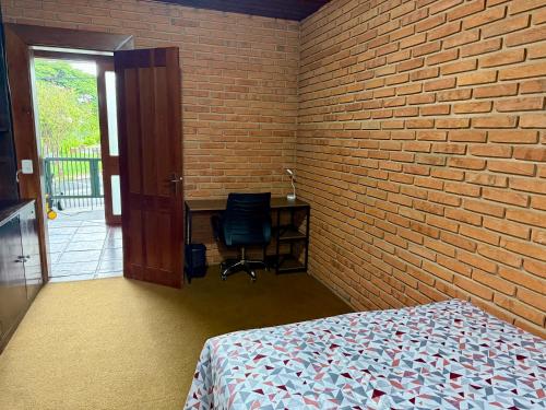 a bedroom with a brick wall and a bed and a chair at Quarto privado completo in Botucatu