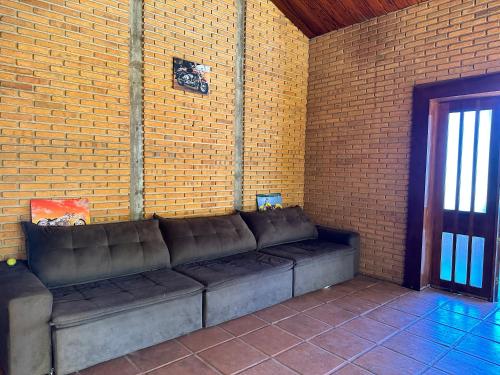 a couch in a room with a brick wall at Quarto privado completo in Botucatu