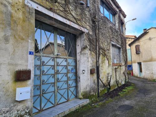an old building with a blue door in an alley at Loft au piémont des Pyrénées Cathares in Sainte-Colombe-sur-lʼHers