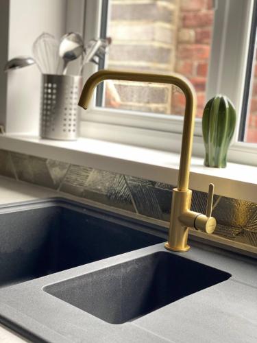 a kitchen sink with a gold faucet next to a window at Central, Contractor&Family Friendly, SmartTV in Sunderland