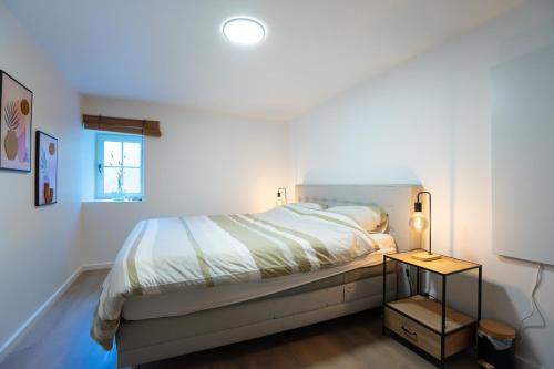 a white bedroom with a bed and a window at La Rocha in La Roche-en-Ardenne
