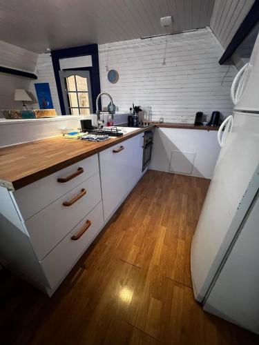 a kitchen with white cabinets and a wooden floor at Le Bleu d 'Audinghen in Audinghen