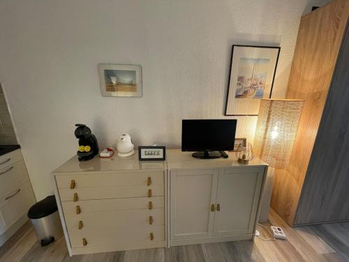 - une commode avec une télévision en haut dans l'établissement L'escapade Marine, au Cap d'Agde