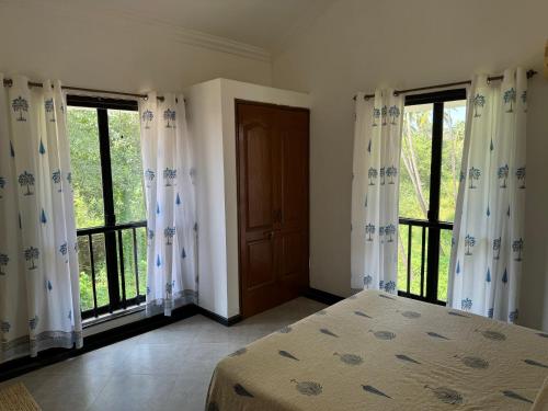 a bedroom with windows and a bed and a door at Cim and Sands in Goa