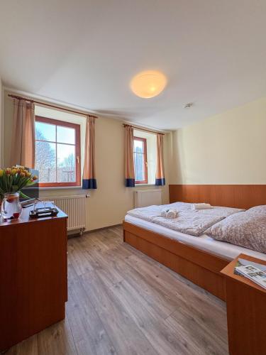 a bedroom with a large bed and two windows at Penzion Čítkův Mlýn in Šluknov