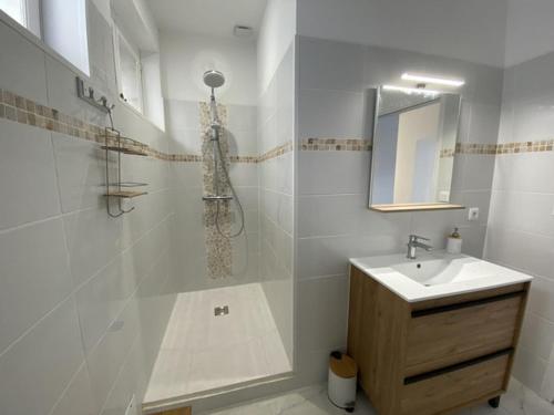une salle de bain blanche avec un lavabo et un miroir dans l'établissement Location maison l'embellie, à La Tremblade