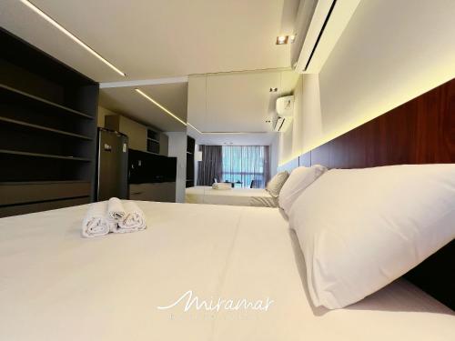 a bedroom with a large white bed with towels on it at Unity - Cabo Branco in Penha