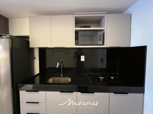 a kitchen with a sink and a microwave at Unity - Cabo Branco in Penha