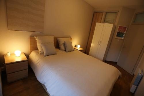 a bedroom with a large white bed with two lamps at Joli appartement au centre de Brest in Brest