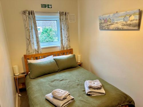 a bedroom with a bed with two towels on it at Rockpool Cottage in Beadnell