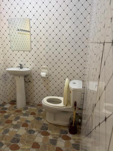 a bathroom with a toilet and a sink at Magdalene Apartments Short Term Rentals in Takoradi