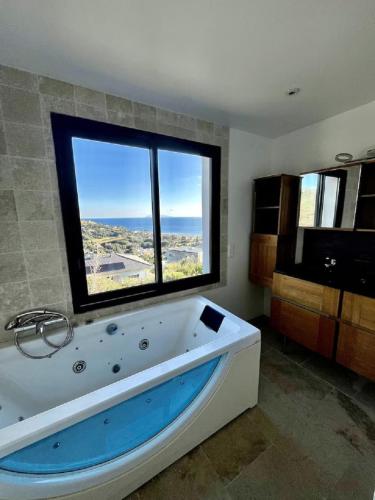 La salle de bains est pourvue d'une grande baignoire et d'une grande fenêtre. dans l'établissement Villa avec piscine vue mer et montagne, à Sisco