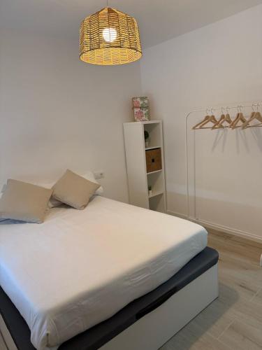 a bedroom with a white bed with a light at Apartamentos Murcia río in Murcia