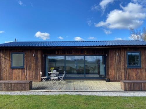 a wooden cabin with a table and chairs on a deck at Wheal Rock - Luxury 2 Bed Lodge in St. Agnes
