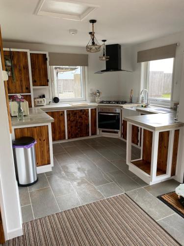 a large kitchen with wooden cabinets and a tile floor at Wheal Rock - Luxury 2 Bed Lodge in St. Agnes