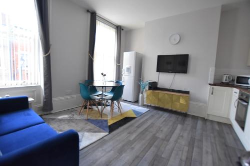 a living room with a blue couch and a table at Dwell Living Argyle Square in Sunderland