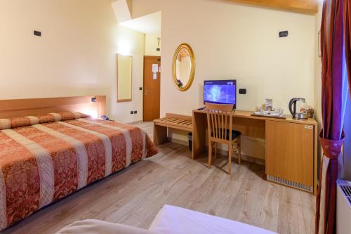 a hotel room with a bed and a desk with a television at Hotel Garni Le Corti in Grosotto