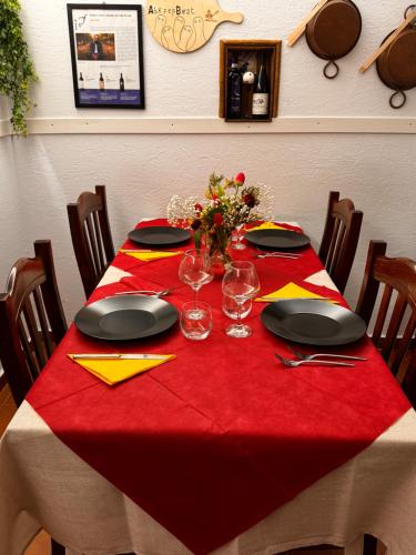 a table with a red table cloth with plates and glasses at B&B VillaDansio in Rezzoaglio