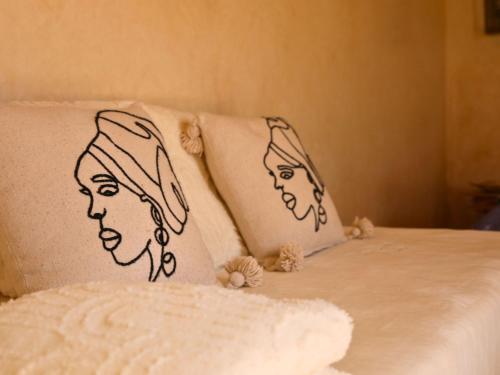 two pillows with faces on them on a bed at L'Hacienda Joud - Privatisation de 5 chambres dans un havre de paix à Marrakech avec piscine & cuisinière privée dans le désert d'Aït Ourir in Aïn er Rmel