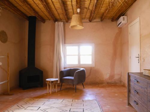 a living room with a chair and a stove at L'Hacienda Joud - Privatisation de 5 chambres dans un havre de paix à Marrakech avec piscine & cuisinière privée dans le désert d'Aït Ourir in Aïn er Rmel