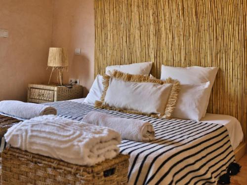 a bedroom with a large bed with white pillows at L'Hacienda Joud - Privatisation de 5 chambres dans un havre de paix à Marrakech avec piscine & cuisinière privée dans le désert d'Aït Ourir in Aïn er Rmel
