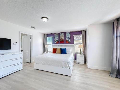 a white bedroom with a bed and a tv at Tranquility Hut, Spacious 4-bedrooms, 4-bathrooms, Pools, free parking in Kissimmee