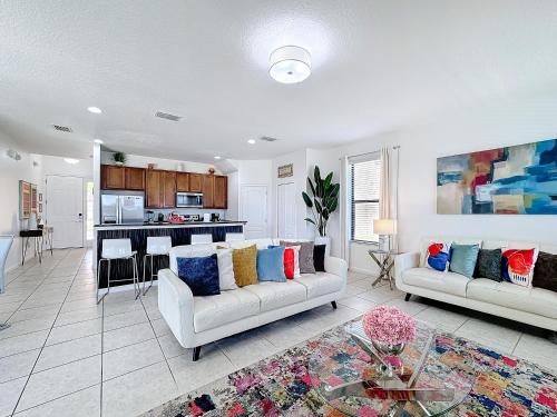 a living room with two couches and a kitchen at Tranquility Hut, Spacious 4-bedrooms, 4-bathrooms, Pools, free parking in Kissimmee