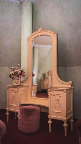 a dressing table with a mirror and a stool at Hétkúti Wellness Hotel in Mór