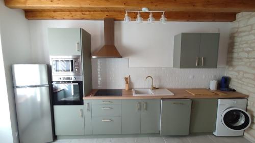 eine Küche mit Kühlschrank und Spüle in der Unterkunft La tanière des trois Ogres, à 10min du Futuroscope in Beaumont