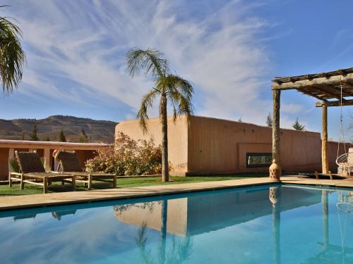 a swimming pool in front of a house with palm trees at L'Hacienda Joud - Privatisation de 5 chambres dans un havre de paix à Marrakech avec piscine & cuisinière privée dans le désert d'Aït Ourir in Aïn er Rmel