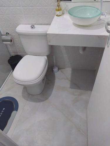a bathroom with a white toilet and a sink at Casa com Piscina - Área da lazer in Guarujá