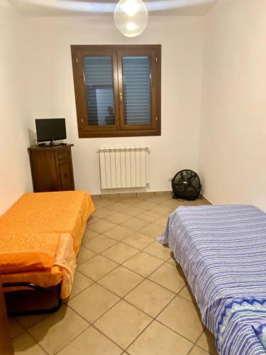 a room with two beds and a window and a tv at Casa Vacanze - Villa Claudia in Leporano Marina
