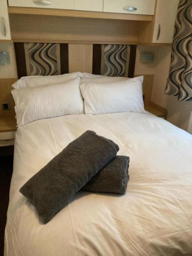 a large white bed with a black pillow on it at Hoburne park Bluebell10 in Burton