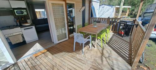 une terrasse en bois avec une table et des chaises sur une maison dans l'établissement Mobil Home Camping 4 étoiles les Oyats, à Seignosse