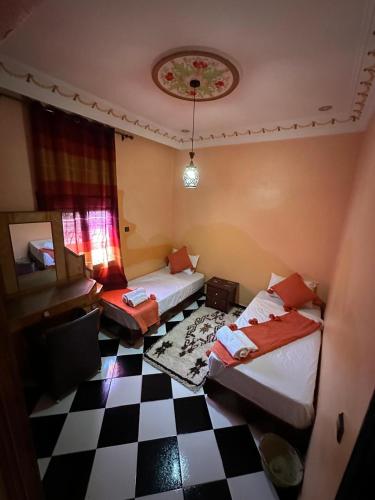 a room with two beds and a checkered floor at Riad Dar Fadma in Ouarzazate