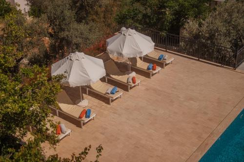 a group of umbrellas and lounge chairs next to a pool at Sunset Apartments with pool in Kalkan in Kalkan