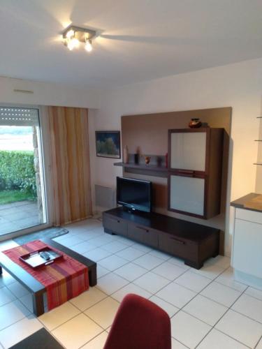 - un salon avec une télévision et une chaise rouge dans l'établissement Appartement vue mer, à Perros-Guirec