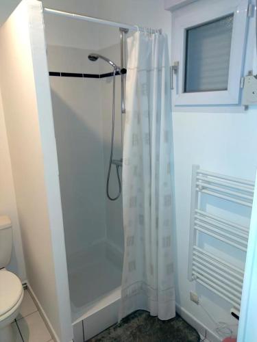 La salle de bains est pourvue d'une douche avec rideau de douche blanc. dans l'établissement Appartement vue mer, à Perros-Guirec