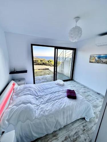 une chambre avec un grand lit avec une grande fenêtre dans l'établissement Villa avec piscine vue mer et montagne, à Sisco