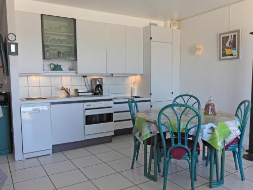 une cuisine avec des armoires blanches et une table et des chaises dans l'établissement Pleine mer, à Fort-Mahon-Plage