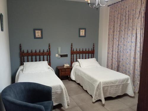 a bedroom with two beds and a blue chair at HOSTAl LUJUAN in Guadalupe