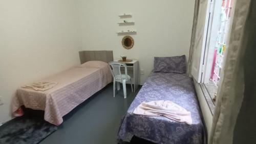 una piccola camera con due letti e una sedia di casa simples na atalaia com preço de hostel ad Aracaju